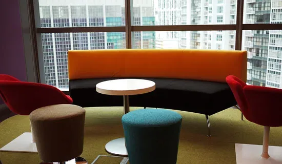 Lounge seating with a curved sofa beside a city-view window